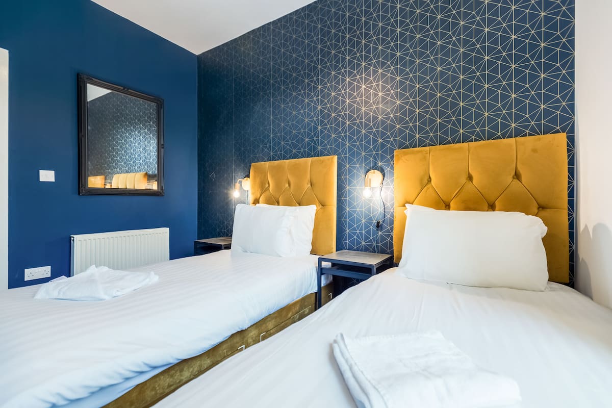 Een hotelkamer met twee bedden, een spiegel en een wand met een geometrisch patroon.