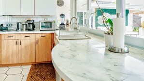 Een moderne keuken met houten kastjes, een marmeren aanrechtblad en een groot raam met uitzicht op de omgeving.