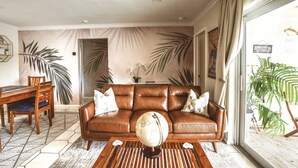 Een woonkamer met een bruine leren bank, een houten salontafel en een wereldbol als decoratie.