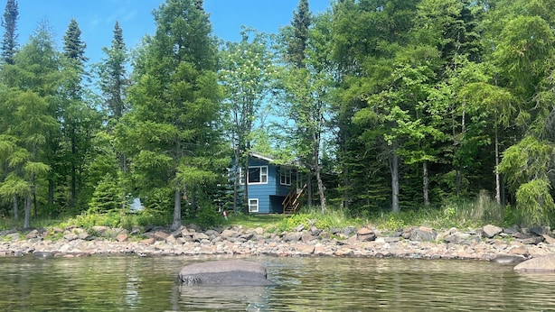 Una cabaña junto a un lago tranquilo, rodeada de un bosque frondoso.