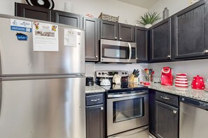 Fully equipped kitchen with stainless steel appliances, dark cabinets, and granite countertops.