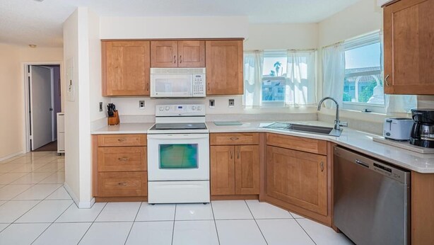Una cucina moderna con mobili in legno, un forno a microonde, un forno, una lavastoviglie e una finestra che offre luce naturale.