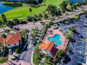 Luchtfoto van een resort met zwembad, parkeerplaats en golfbaan.