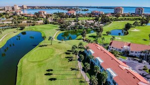 Un campo da golf con ostacoli acquatici, un club house e edifici circostanti.