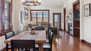 A spacious dining area with a wooden table and chairs, a chandelier, and large windows offering a view of the outdoors. - Outpost: Grand View 3230 - Air Conditioning! (Jackson)