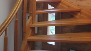 Eine Wendeltreppe aus Holz mit Blick ins Freie durch ein Fenster.