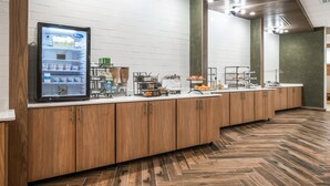 Cozinha moderna com frigorífico embutido, máquina de café e diversos alimentos na bancada.