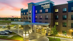 Um hotel Fairfield Inn & Suites com fachada de tijolos moderna, entrada bem iluminada e área de estacionamento.
