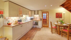 Une cuisine avec des meubles blancs, un four à micro-ondes et une cuisinière. On y trouve également un coin repas avec une table et des chaises.