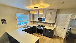 Una cocina moderna con una isla central, electrodomésticos de acero inoxidable e iluminación colgante.