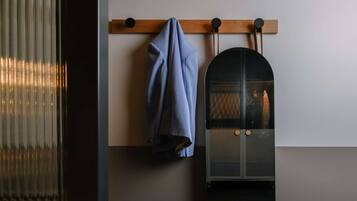 A room with a large mirror, a hanging coat rack, and a skateboard.