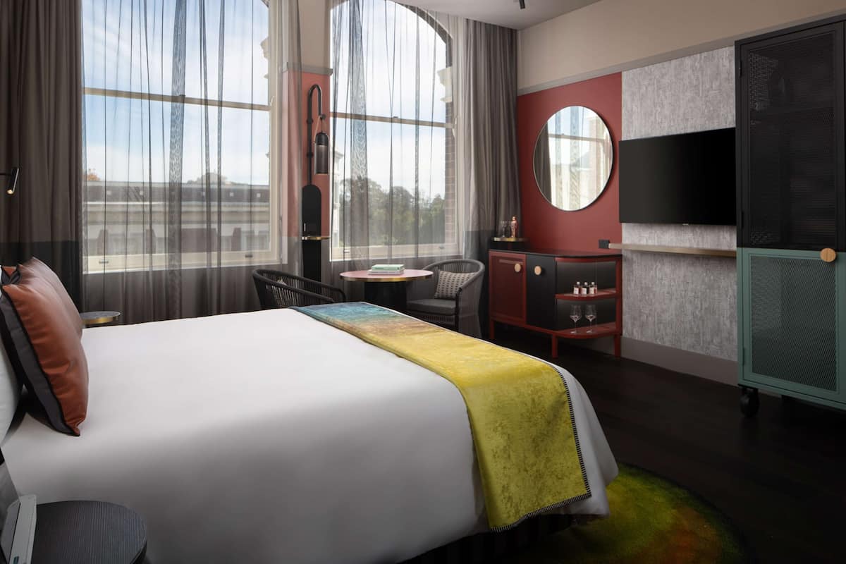 Una habitación de hotel con una cama grande, un escritorio, una silla, un televisor y un armario.