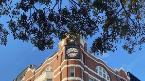 A multi-story building with a prominent clock tower, large windows, and a modern entrance area. - QT Newcastle (Newcastle)