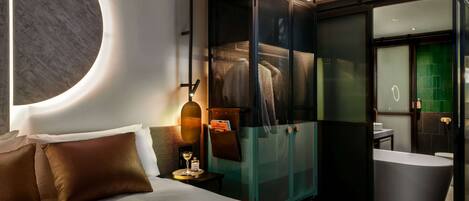 Una habitación de hotel moderna con una cama grande, un armario con puertas de cristal, un baño independiente con bañera y un diseño de pared único.