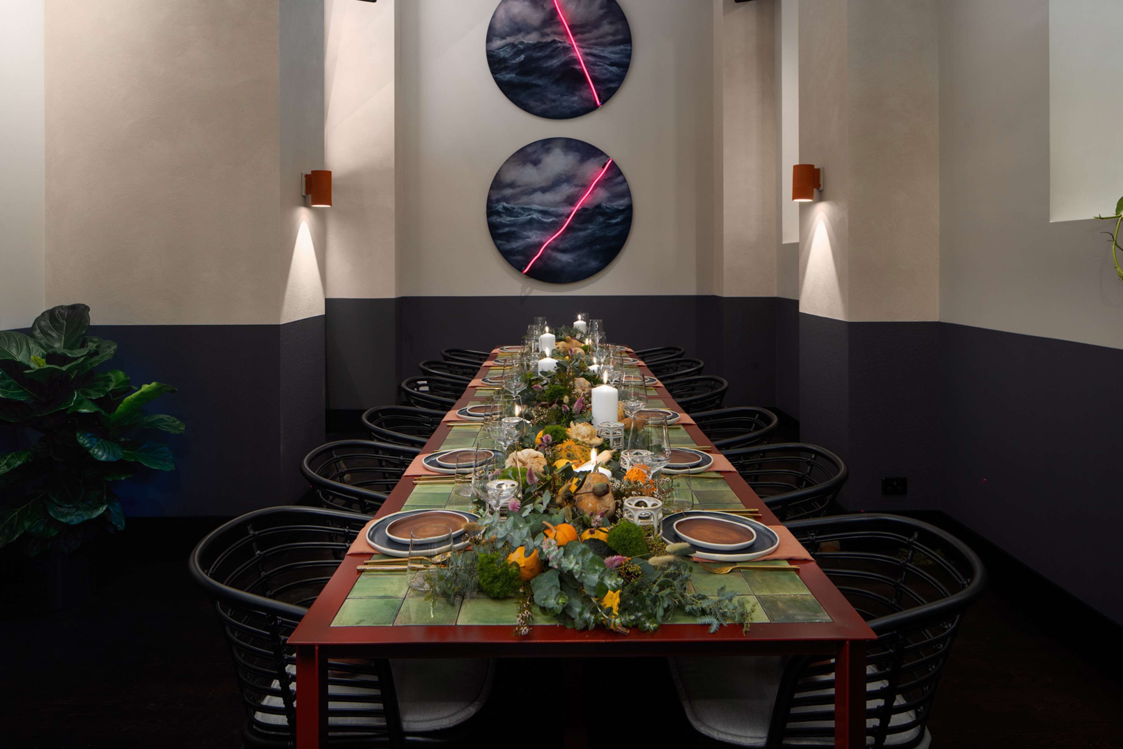 A long dining table set with glassware, plates, and a centerpiece of flowers and foliage.
