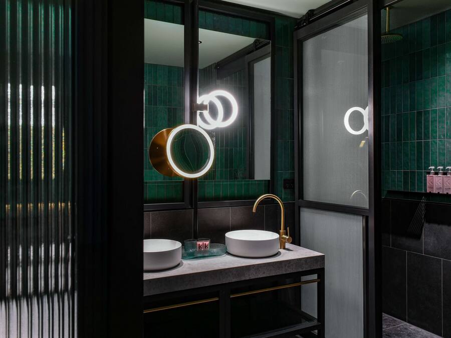 A modern bathroom with two sinks, a mirror, and a vanity.