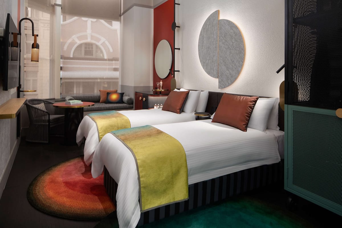 Una habitación de hotel con dos camas, un sofá, una mesita y un televisor.