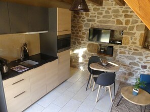 A compact kitchen with a built-in microwave, a sink, and a dining area with two chairs and a small table.