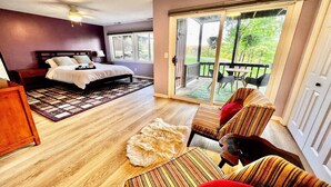 Une chambre avec un lit, un plancher en bois, un tapis, une peau de bête et un balcon avec des chaises.