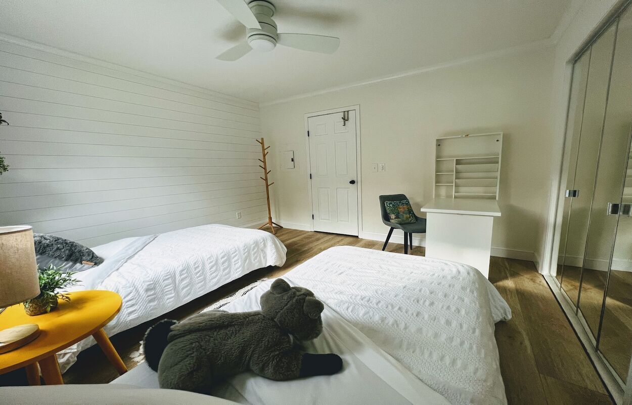 Ein Schlafzimmer mit zwei Betten, einem Deckenventilator, einem Stuhl und einem Kleiderschrank.