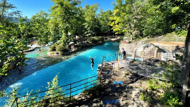 Une piscine naturelle entourée d’une végétation luxuriante et d’un paysage rocheux.