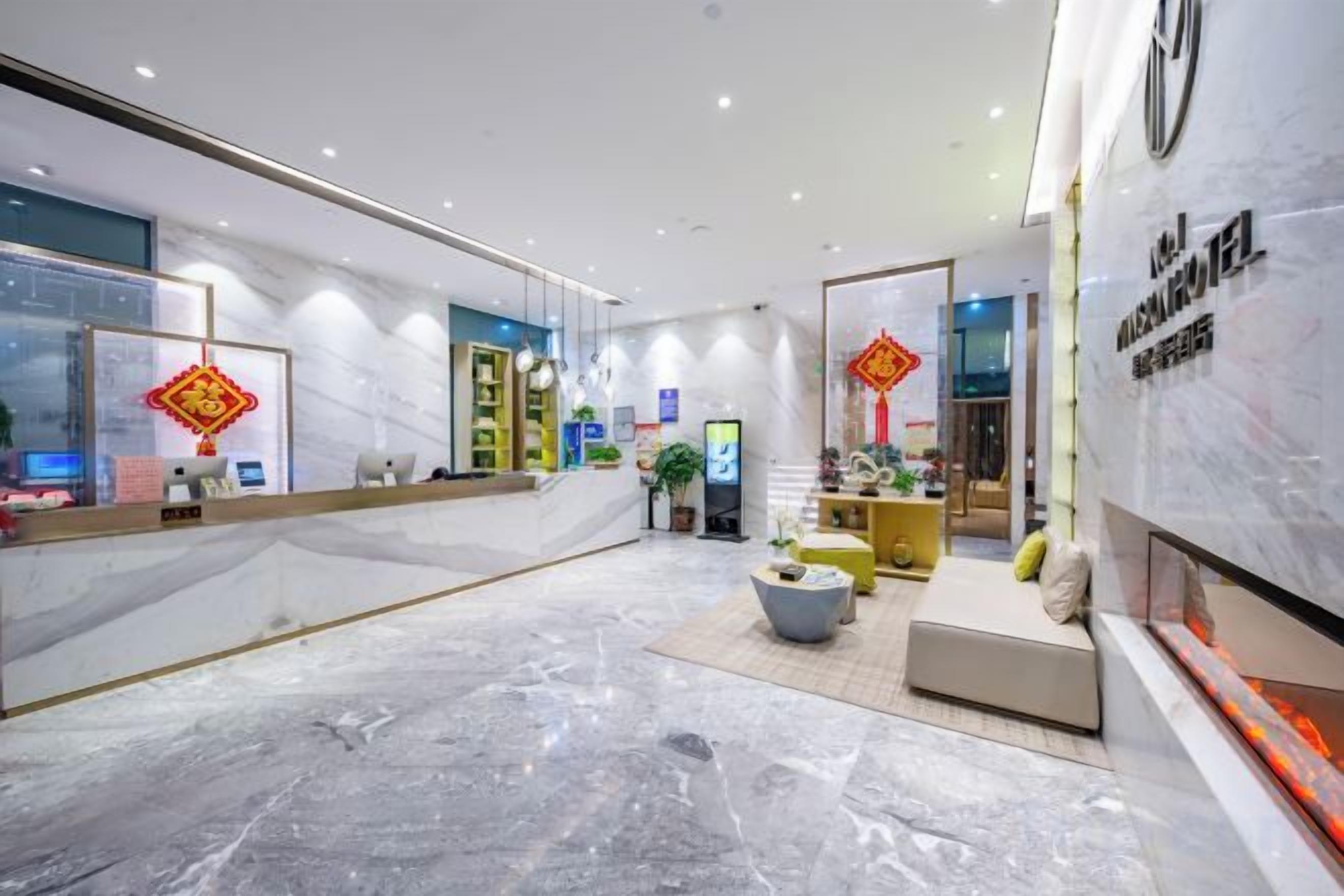A hotel lobby with a reception desk, seating area, and a large mirror reflecting the interior.