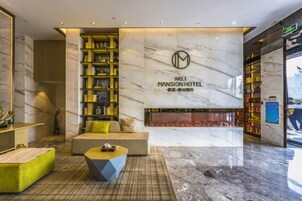 A modern lobby with a seating area, a fireplace, and a large marble wall with the hotel name.
