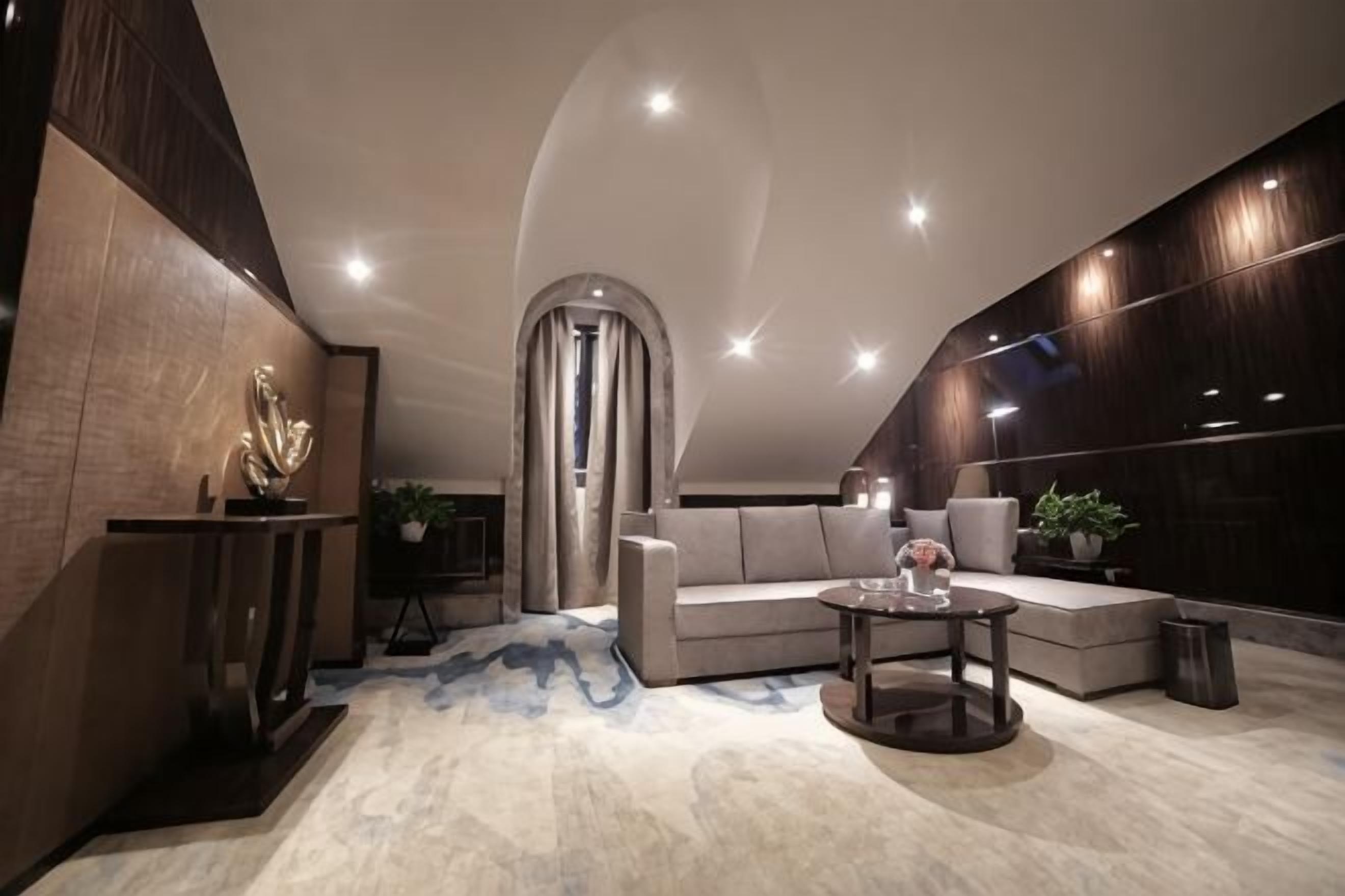 A modern interior with a curved ceiling, a sofa, a coffee table, and a decorative sculpture.