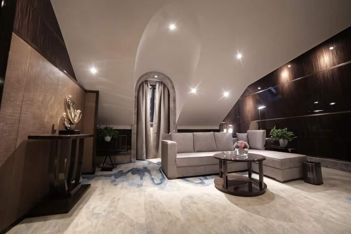 Um interior moderno com teto curvo, um sofá, uma mesa de centro e uma escultura decorativa.
