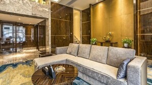 Un vestíbulo moderno con un sofá modular, una mesa de centro redonda y un mostrador de recepción de mármol.
