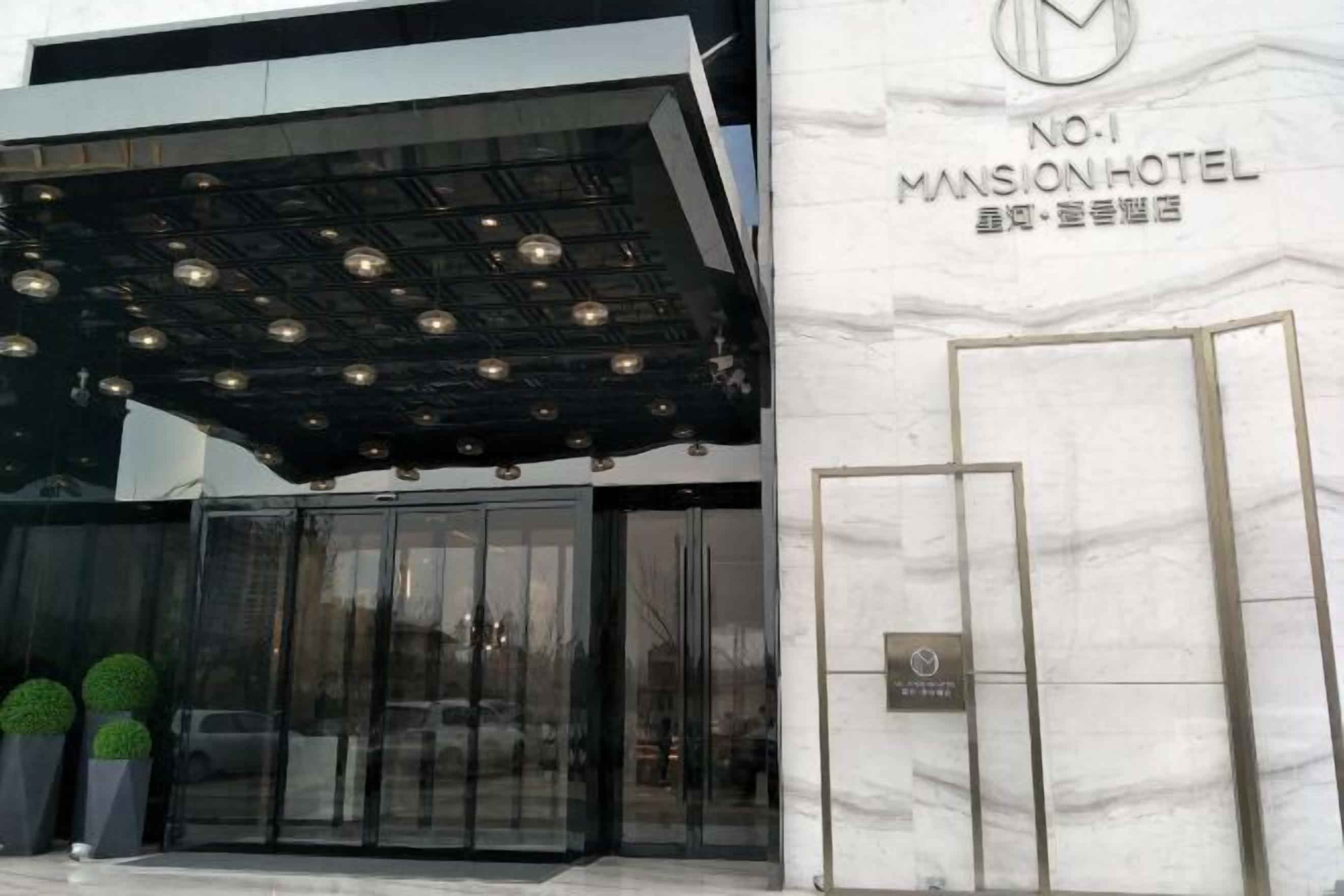 The exterior of No.1 Mansion Hotel with a modern entrance featuring glass doors and a metal canopy.