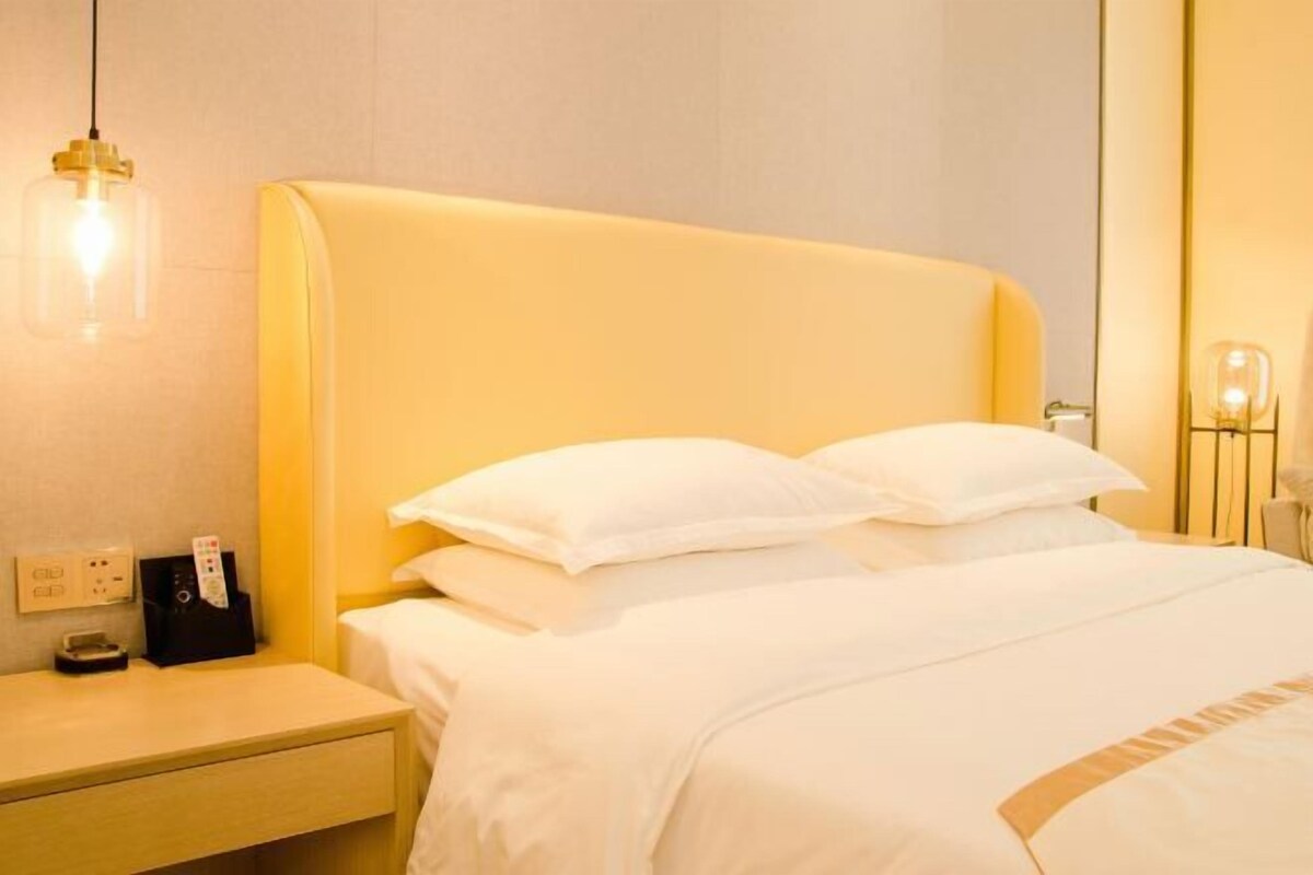 Una habitación de hotel con una cama grande, una mesita de noche y una lámpara fijada a la pared.