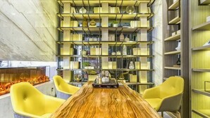 Un interior moderno con una mesa de madera, sillas amarillas y una pared llena de estanterías.