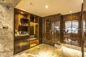 Un baño con piso de mármol, tocador de madera y espejo.