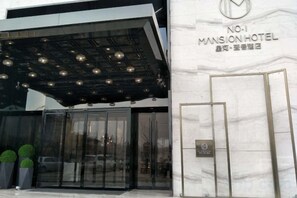 A modern building with a glass entrance and a sign for 'No.1 Mansion Hotel.'