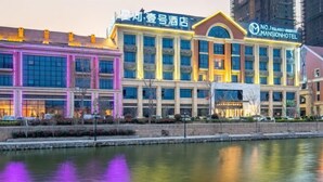 Un hotel de varios pisos con un letrero llamativo que dice "Mansion Hotel" y su reflejo en el agua de enfrente.