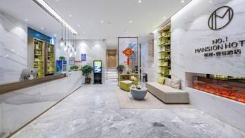 A hotel lobby with a reception desk, seating area, and a fireplace.
