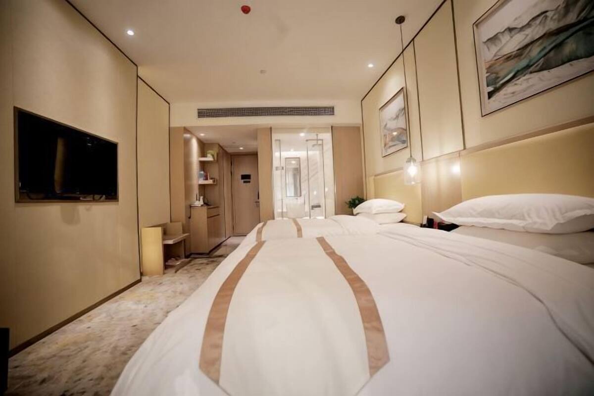 Quarto de hotel com uma cama grande, televisão, escrivaninha e banheiro.