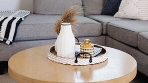 Un salon avec un canapé gris, une table basse ronde en bois et un luminaire suspendu.