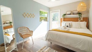 Une chambre à coucher avec un lit, une chaise, un miroir et un ventilateur de plafond.