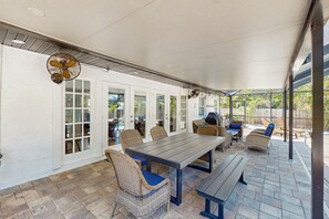 Relax in comfort on this covered patio with a long table and wicker chairs.