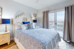 Relax in this inviting bedroom with a large bed, nightstand, and dresser, plus a balcony offering a city view.