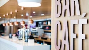 Un comptoir de bar avec une enseigne indiquant « BAR CAFÉ » et des lampes suspendues.