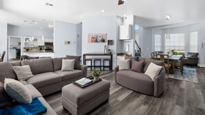 Ein modernes Wohnzimmer mit zwei Sofas, einem Couchtisch und einem Essbereich mit Tisch und Stühlen.