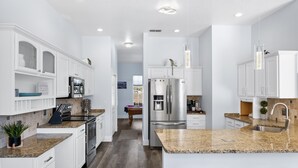 Eine moderne Küche mit weißen Schränken, Granit Arbeitsplatten, Edelstahlgeräten und Einbauleuchten.