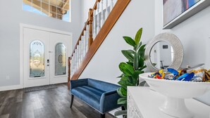 Ein geräumiger Eingangsbereich mit einer Holztreppe, einer blauen Bank und einem weißen Empfangstresen mit dekorativem Spiegel.