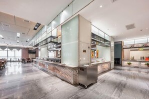 A modern hotel lobby with a marble floor, a reception desk, and a glass partition wall.
