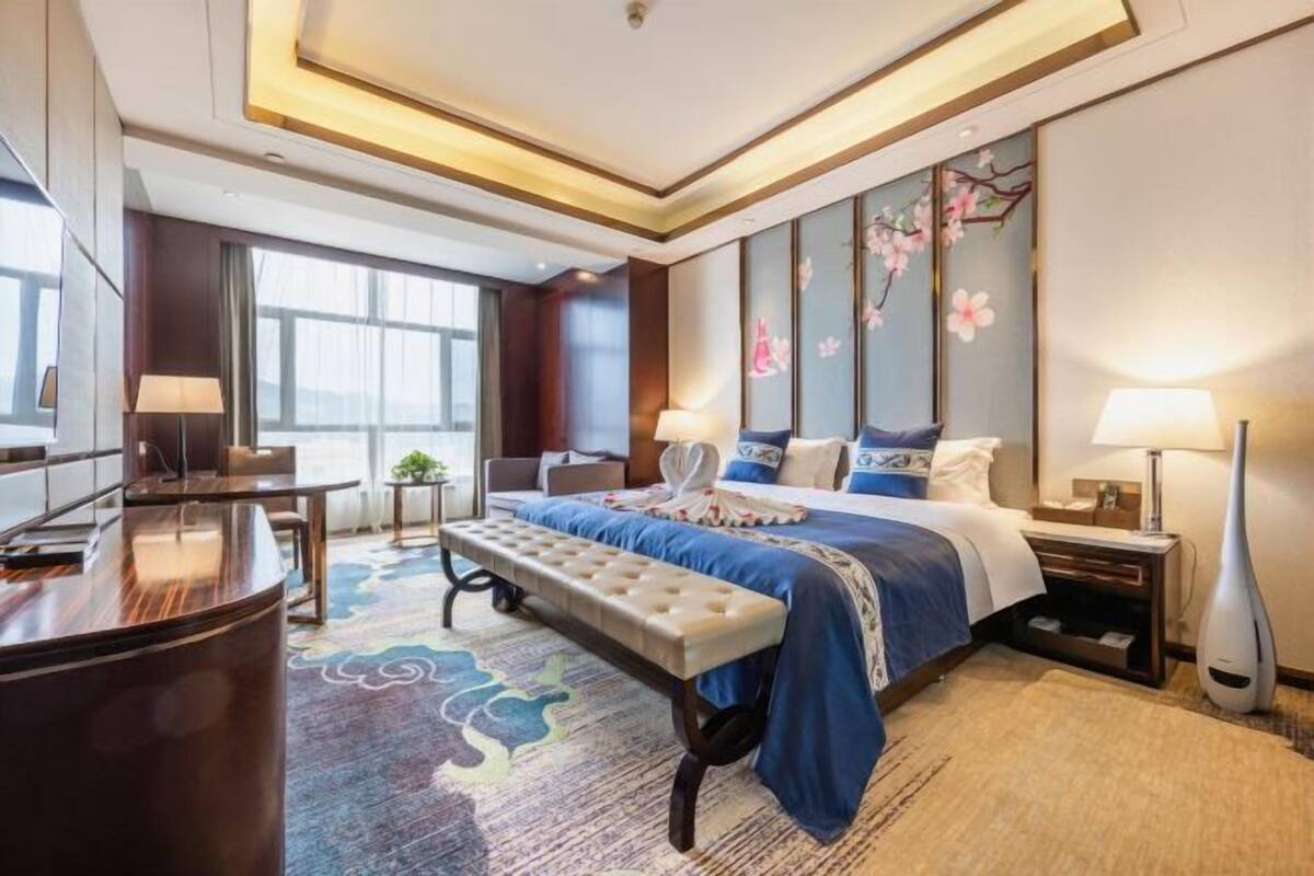 A modern hotel room with a large bed, a desk, and a seating area.
