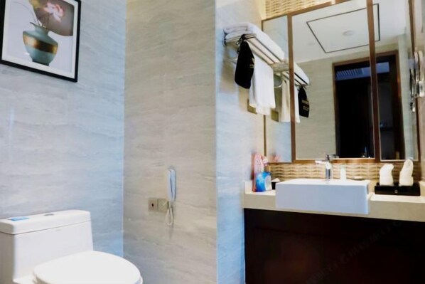 Een moderne badkamer met toilet, wastafel en grote spiegel. Handdoekrek met handdoeken en een klein schapje met toiletartikelen.