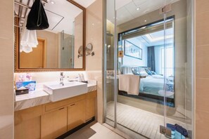 A modern bathroom with a large mirror, a white sink, and a glass shower enclosure. - Hezhou Hongrui International Hotel (Linxia)
